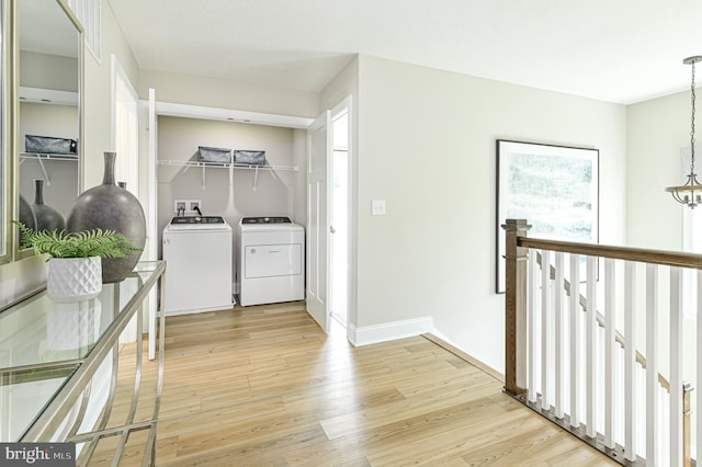 hallway featuring an inviting chandelier, light hardwood / wood-style flooring, and washer and dryer