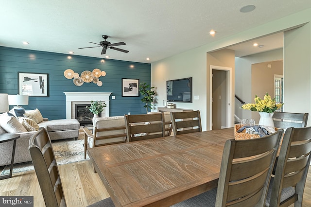 dining area with wooden walls, ceiling fan, and light wood-type flooring