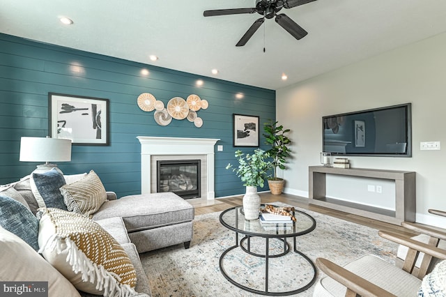 living room featuring wooden walls, light hardwood / wood-style floors, and ceiling fan