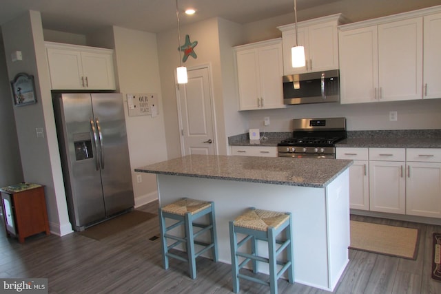 kitchen featuring stainless steel appliances, a center island, white cabinetry, and dark hardwood / wood-style flooring