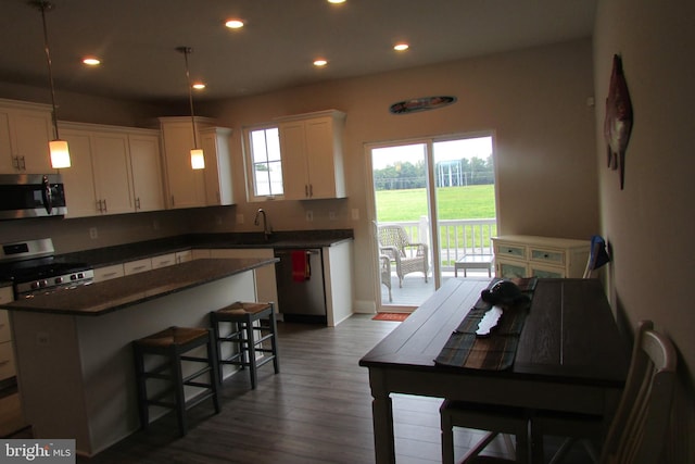 kitchen with hanging light fixtures, dark hardwood / wood-style flooring, stainless steel appliances, a kitchen bar, and a center island