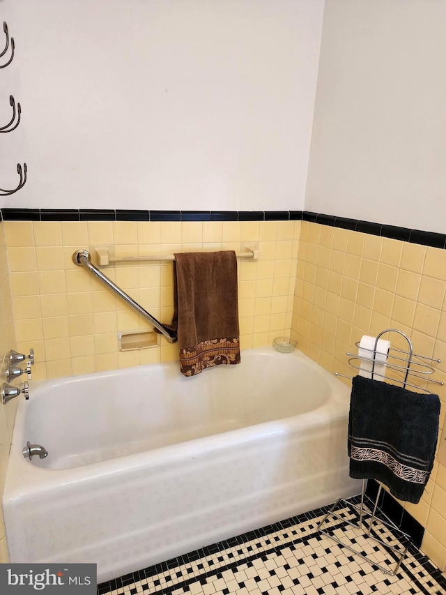 bathroom featuring tile walls and a bath