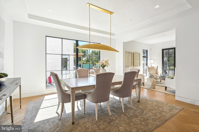 dining room featuring a raised ceiling and light parquet flooring