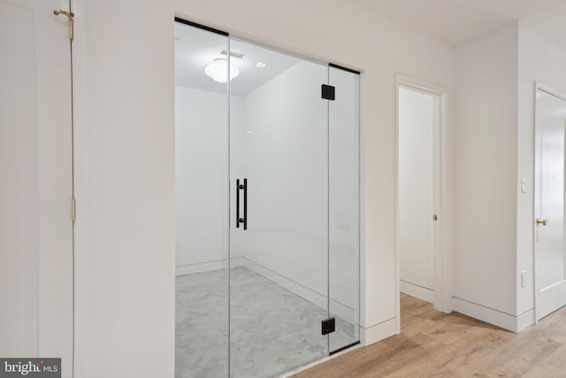 bathroom with hardwood / wood-style floors and a shower with shower door