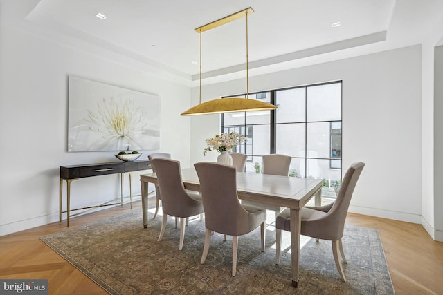 dining area with light parquet floors and a raised ceiling