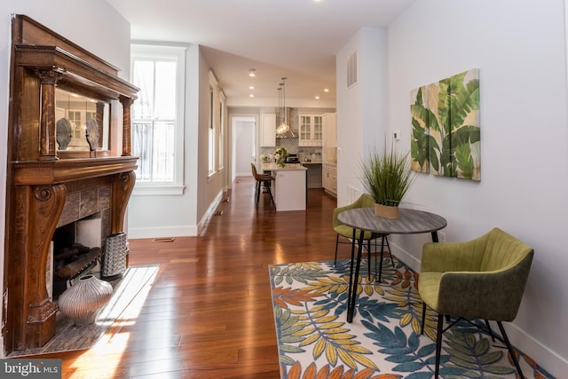 interior space featuring a tiled fireplace and dark hardwood / wood-style floors