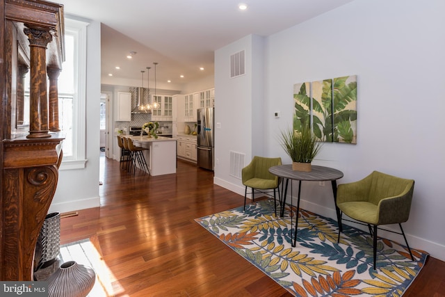 living area with an inviting chandelier, decorative columns, and dark wood-type flooring