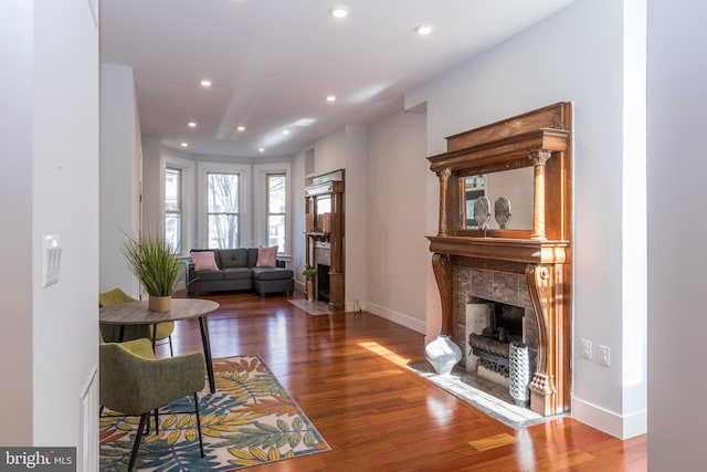 living room with dark wood-type flooring and a tiled fireplace