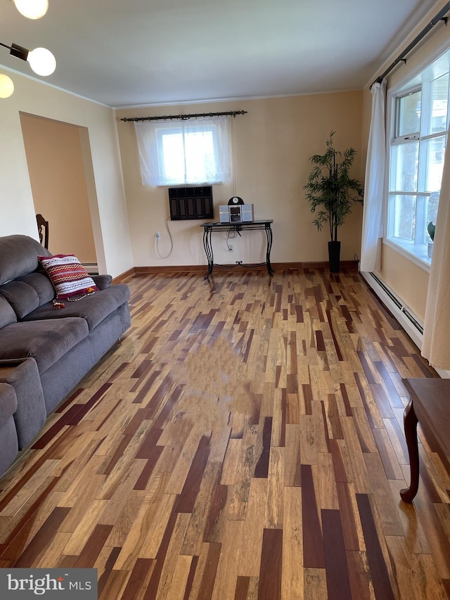 living room featuring plenty of natural light, a baseboard heating unit, and wood-type flooring