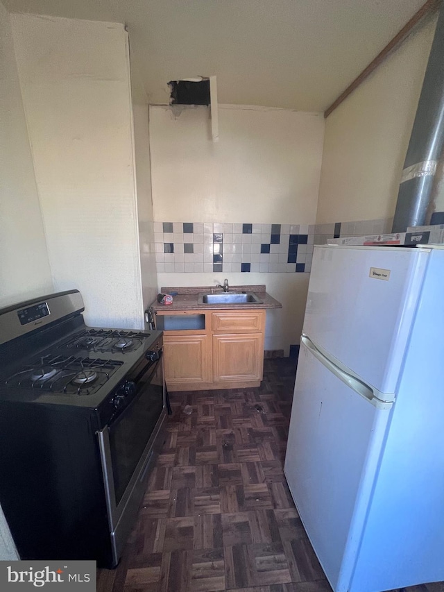 kitchen featuring white fridge, backsplash, sink, dark parquet flooring, and stainless steel gas range