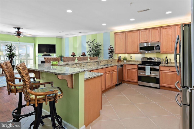 kitchen with light tile flooring, ceiling fan, appliances with stainless steel finishes, light stone counters, and sink