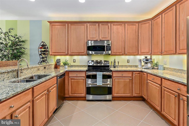 kitchen with sink, appliances with stainless steel finishes, light tile flooring, and light stone countertops