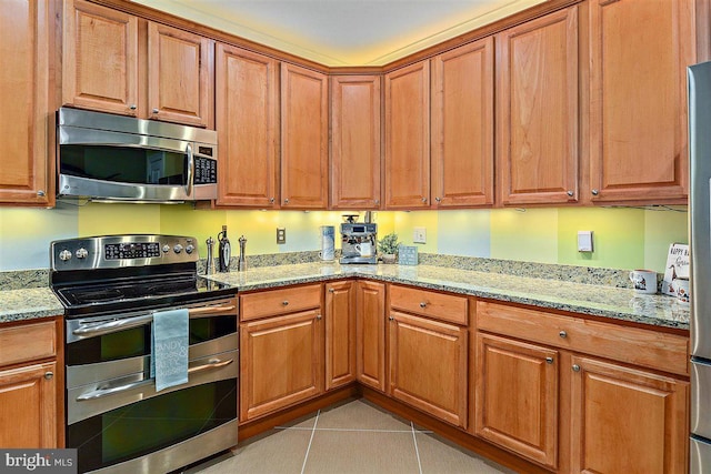 kitchen featuring light stone countertops, stainless steel appliances, and light tile floors