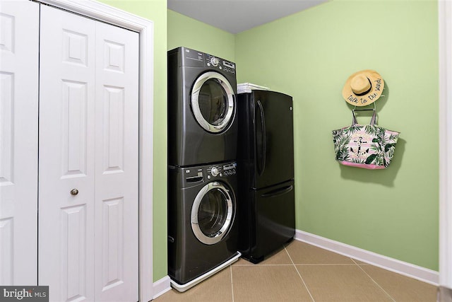 clothes washing area featuring stacked washer / dryer and light tile floors