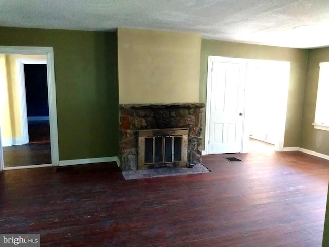 unfurnished living room featuring a fireplace, dark hardwood / wood-style flooring, and a textured ceiling