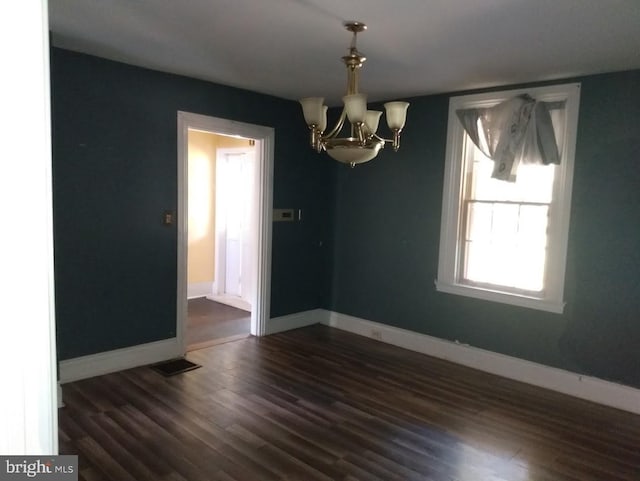 unfurnished dining area featuring dark hardwood / wood-style flooring and a chandelier