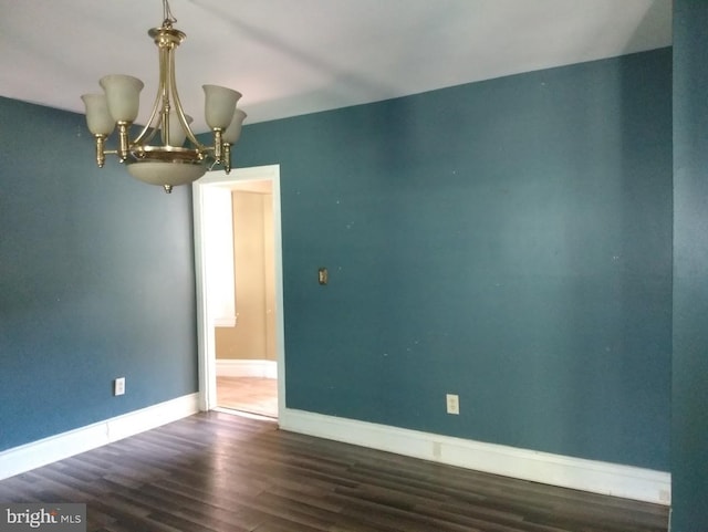 spare room with dark hardwood / wood-style flooring and a notable chandelier