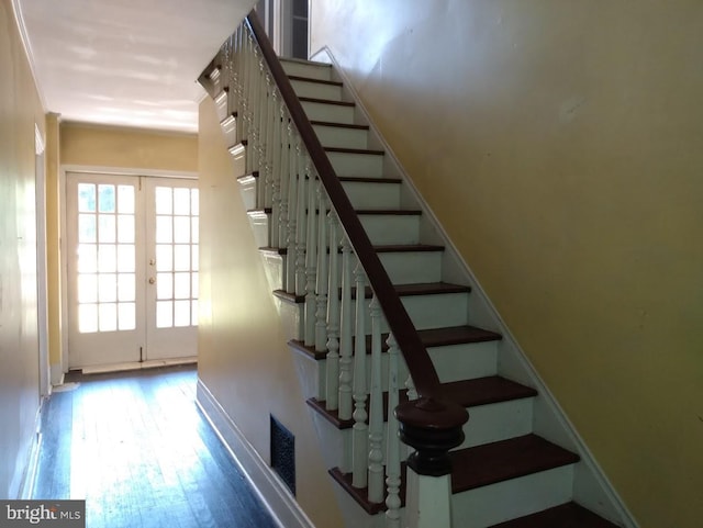 stairway with french doors and hardwood / wood-style floors