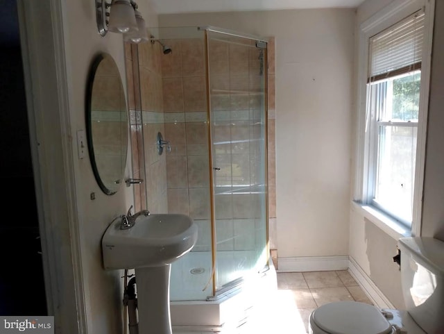 bathroom with toilet, plenty of natural light, a shower with shower door, and tile patterned flooring