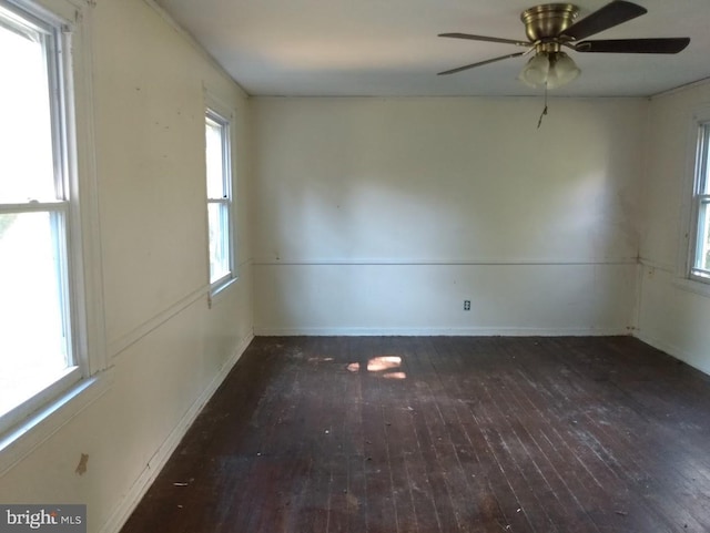 empty room with dark hardwood / wood-style floors, a wealth of natural light, and ceiling fan