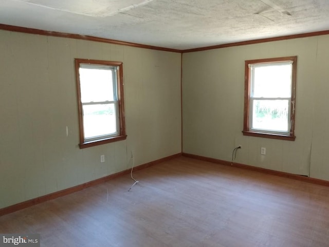 spare room with plenty of natural light, light wood-type flooring, and ornamental molding