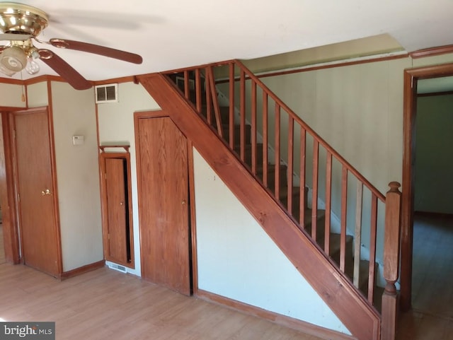 stairs featuring ceiling fan and hardwood / wood-style floors