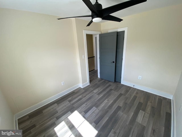 unfurnished bedroom with ceiling fan and dark wood-type flooring