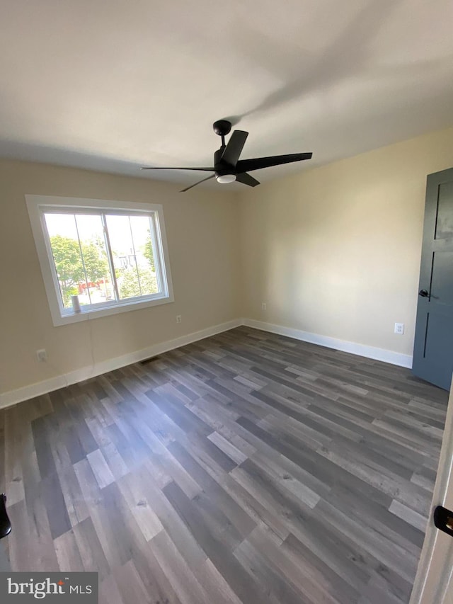 spare room with ceiling fan and dark wood-type flooring