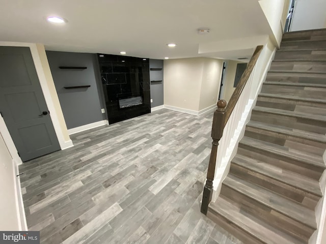 basement featuring a tiled fireplace and hardwood / wood-style floors