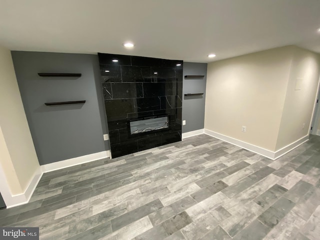 unfurnished living room with hardwood / wood-style floors and a tiled fireplace