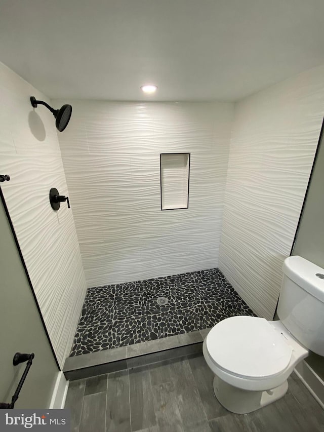 bathroom with tiled shower and toilet