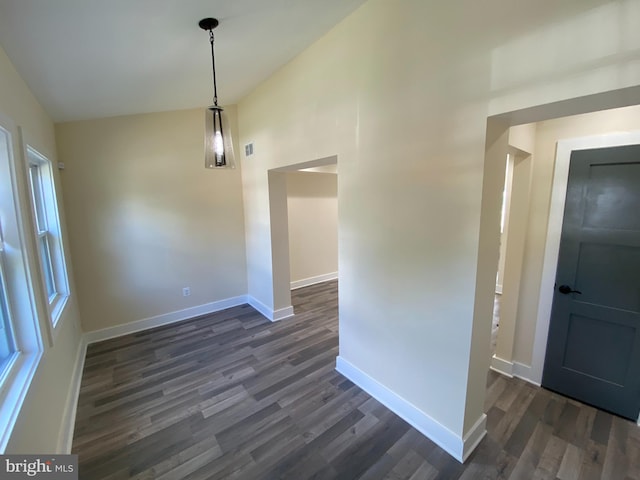 unfurnished dining area with vaulted ceiling and dark wood-type flooring