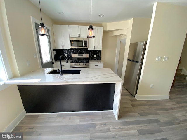 kitchen with tasteful backsplash, stainless steel appliances, sink, white cabinets, and hanging light fixtures