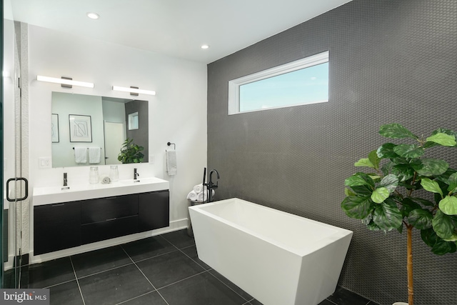 bathroom featuring a bathtub, double sink vanity, and tile flooring