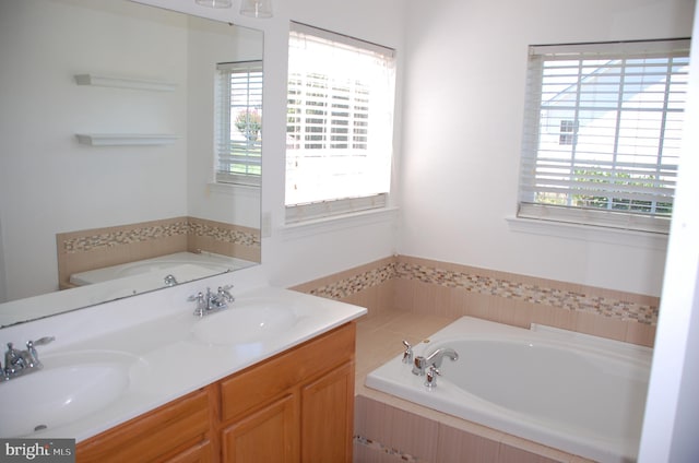 bathroom featuring dual vanity and tiled tub