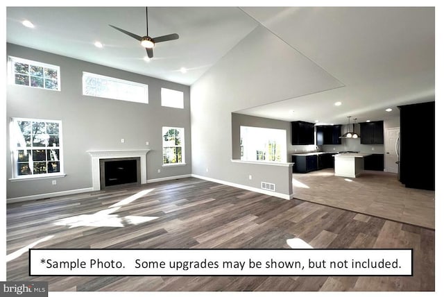 unfurnished living room featuring ceiling fan, dark hardwood / wood-style floors, and a high ceiling