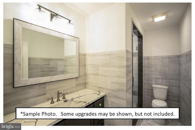 bathroom featuring toilet, vanity, and tile walls