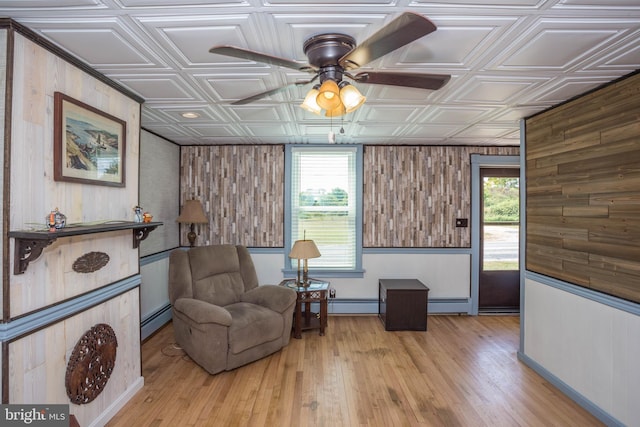 sitting room with a healthy amount of sunlight, ceiling fan, a baseboard heating unit, and light wood-type flooring