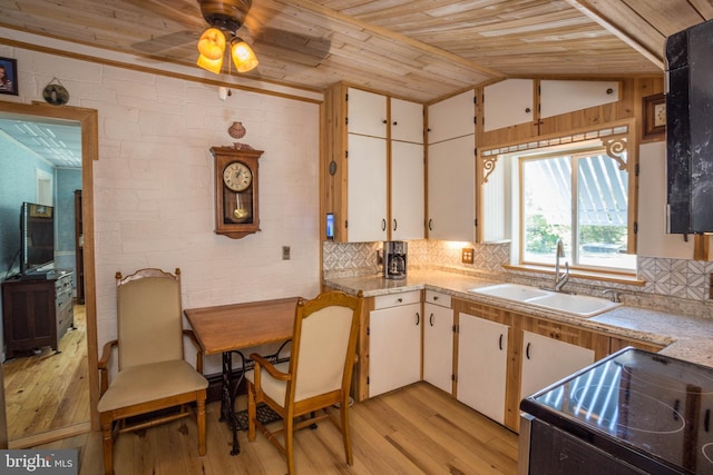 kitchen with light wood-type flooring, white cabinetry, range, and sink