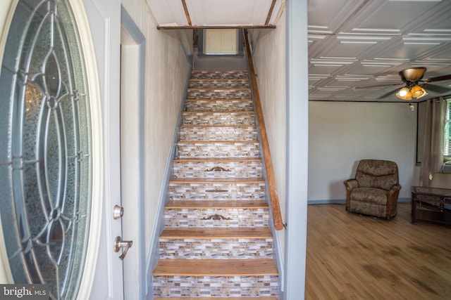 stairway with ceiling fan and wood-type flooring