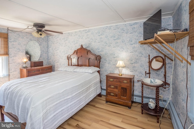 bedroom with ceiling fan, a baseboard heating unit, and light wood-type flooring