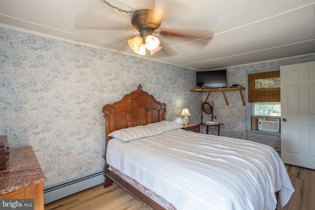 bedroom with a baseboard heating unit, crown molding, light wood-type flooring, and ceiling fan