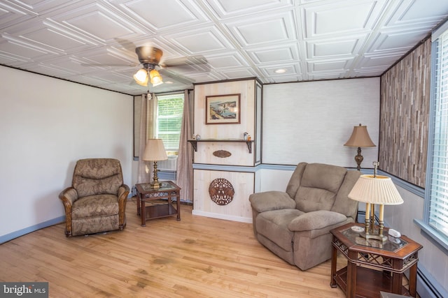 sitting room with light hardwood / wood-style flooring, wood walls, ceiling fan, and a baseboard heating unit