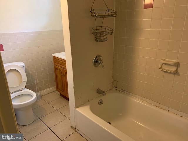 full bathroom with tile walls, toilet, tiled shower / bath, tile flooring, and vanity