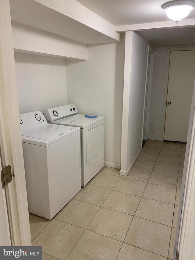 clothes washing area with washing machine and clothes dryer and light tile floors