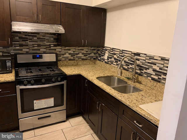 kitchen with light stone countertops, tasteful backsplash, gas stove, and sink