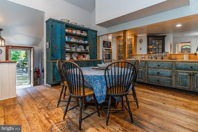 dining room featuring built in features, lofted ceiling, and wood-type flooring