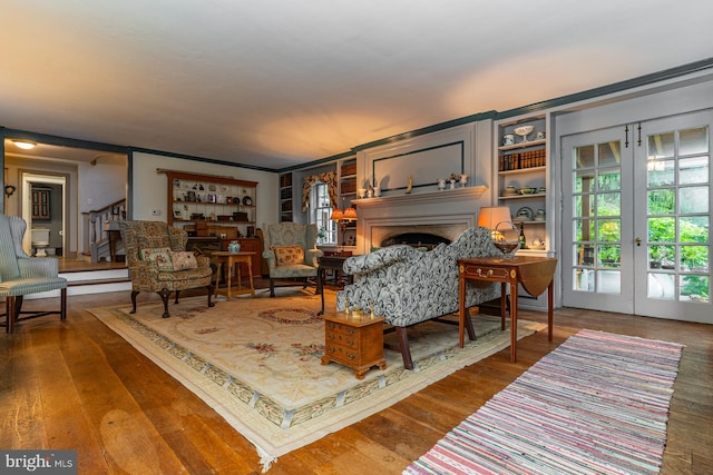 living room featuring crown molding, dark hardwood / wood-style floors, built in shelves, and french doors