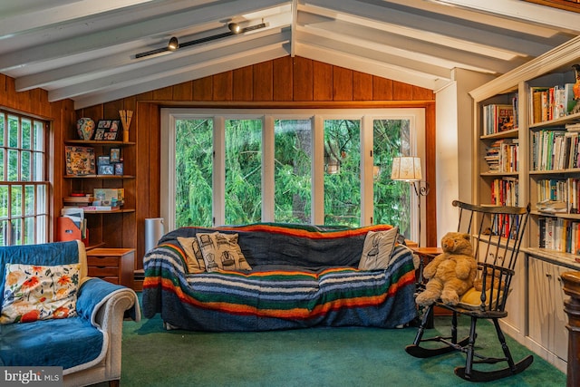 living room with wood walls, lofted ceiling with beams, and plenty of natural light