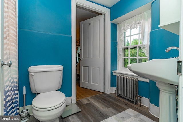 bathroom featuring wood-type flooring, toilet, and radiator